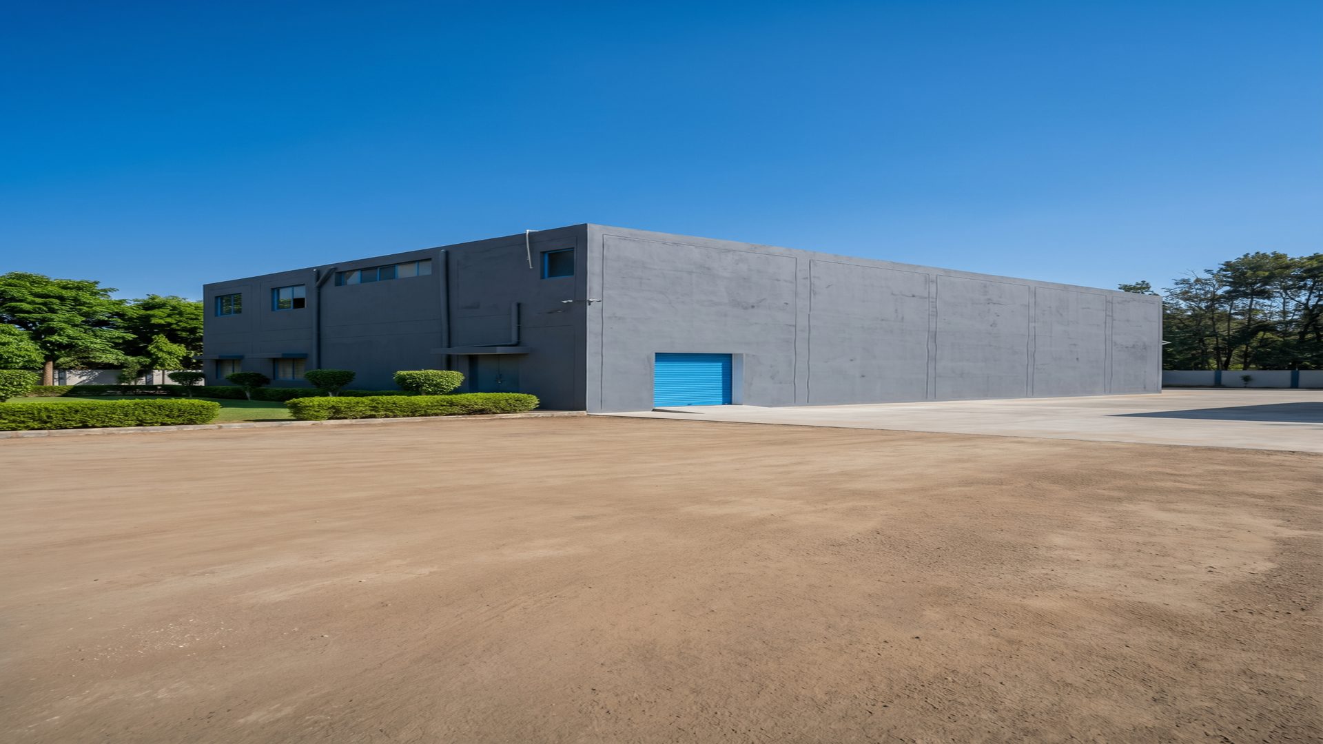 Warehouse exterior with large paved yard and blue loading shutter